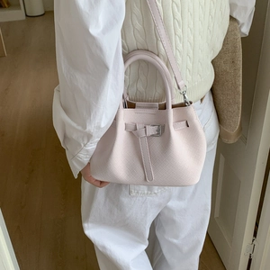 Detailed side view of a light pink woven bucket bag with leather strap on a model