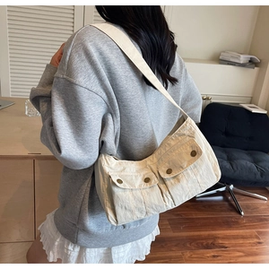 Close-up of beige textured shoulder bag showing dual cargo pockets with bronze buttons