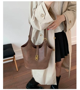 Brown vintage leather bucket bag with gold buckle detail styled with beige trench coat