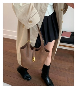 Close-up of brown leather bucket bag with golden metal buckle and minimalist vintage style