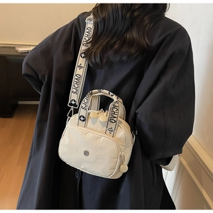 Mini-Boston-Tasche aus cremeweißem Nylon mit bedrucktem Schultergurt an einem Model