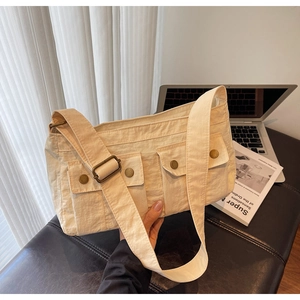 Beige large-capacity shoulder bag with double front flap pockets on a leather bench