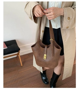 Detailed view of brown vintage leather bucket bag with elegant gold buckle accent