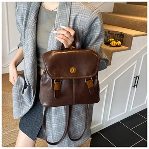 Detailed view of a dark brown vintage backpack featuring golden metal twist-lock and straps