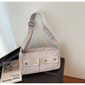 Detail of light beige utility shoulder bag with dual flap pockets and antique bronze buckles
