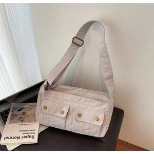 Close-up of beige shoulder bag with two front snap pockets and adjustable strap for commuting