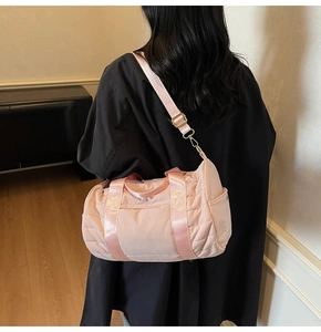 Detail view of pink quilted nylon travel bag with adjustable strap and side pocket