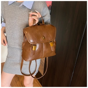 Brown vintage faux leather backpack with metallic buckle closure on a stylish model