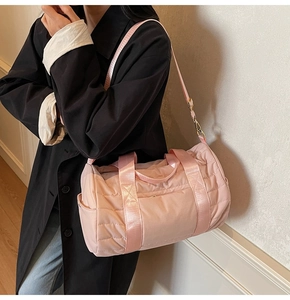 Pink quilted nylon gym bag with adjustable shoulder strap worn by a model in a casual setting
