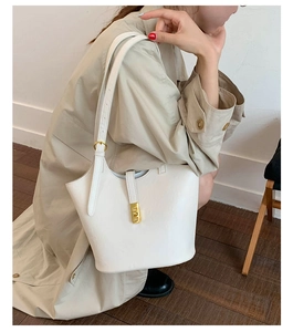 Detailed view of white leather bucket bag with elegant gold metal buckle and strap