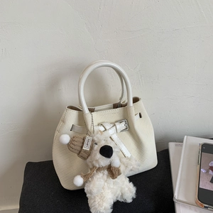 Close-up of beige woven leather bucket bag with silver buckle and cute teddy bear charm