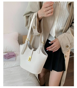 Close-up of beige leather bucket bag with elegant gold rectangular twist lock detail