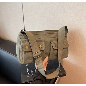 Detailed close-up of olive green canvas shoulder bag with dual front utility pockets
