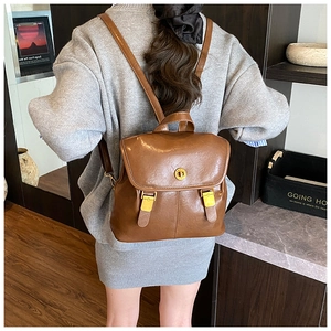 Detail view of vintage brown leather backpack with golden rotary lock and buckle closure