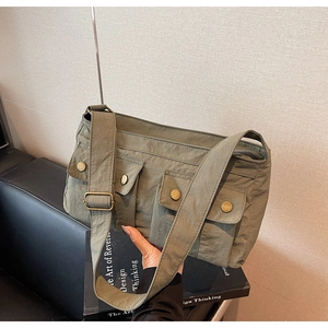 Detail of olive green nylon shoulder bag with functional multi-pocket utility design
