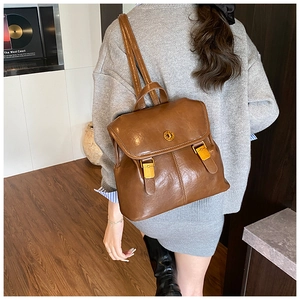 Close-up of vintage brown leather backpack with golden metallic buckles and turn-lock
