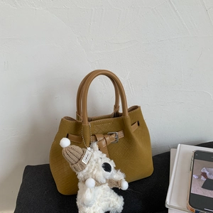 Detail of mustard yellow woven bucket bag with a cute teddy bear plush pendant charm