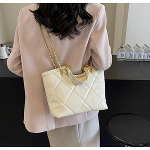 Quilted white tote bag with chain strap shown on model in a modern lifestyle setting