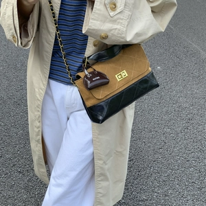 Detail of a quilted patchwork crossbody bag featuring gold hardware and a branded charm