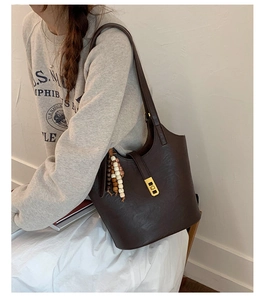 Detail of dark brown leather bucket bag with gold buckle and vintage wooden bead charm
