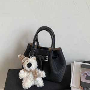 Detail of black woven leather bucket bag with cute bear charm and silver buckle strap