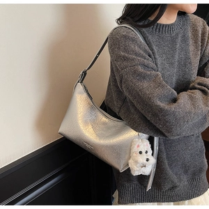 Detailed side view of silver metallic crackle texture bag with white plush dog charm