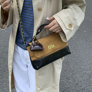 Close-up of quilted two-tone chain bag with golden twist lock and mini purse charm