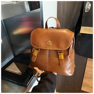 Detail of vintage brown leather backpack showing metal twist lock and top handle grip