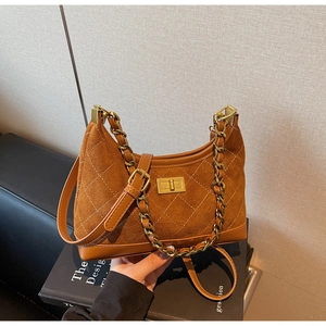 Detailed view of brown suede bag with diamond quilting and gold chain strap