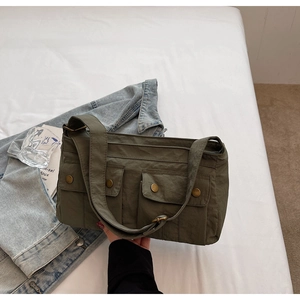 Detail of army green canvas shoulder bag featuring dual front pockets and retro metal buttons
