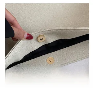 Detalle del cierre magnético dorado y la textura de grano cruzado en el bolso beige