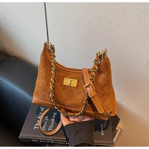 Detail of brown suede crossbody bag with diamond quilting and gold chain strap