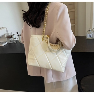 Detail of cream quilted tote bag featuring metal chain strap and large capacity design
