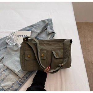 Detail of army green canvas shoulder bag with multiple pockets and retro metal snaps
