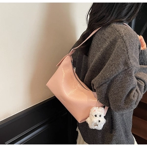 Detail of pink glossy leather hobo bag with cute white plush dog charm on strap