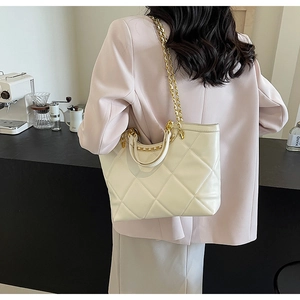 Close-up of quilted cream tote bag with gold chain strap and elegant faux leather texture