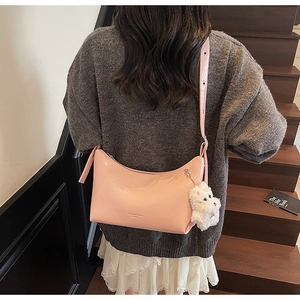 Detail of pink leather shoulder bag with a cute white plush puppy charm on the side