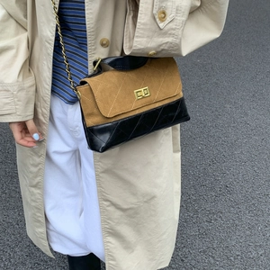 Close-up of retro quilted brown suede and black leather bag with gold twist lock