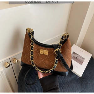 Detailed view of the diamond quilted texture and gold turn-lock on the suede shoulder bag