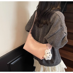 Detail of light pink crescent underarm bag with a cute white plush puppy charm pendant