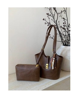 Macro detail of retro dark brown leather bucket bag with gold clasp and bead tassel