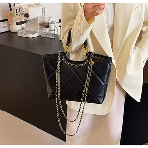 Detail view of black quilted tote bag with gold chain straps and PU leather texture