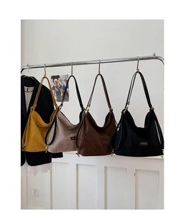 Four colors of matte faux suede bucket bags hanging on a rack showing variety and design