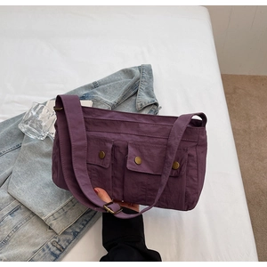Detailed view of purple nylon shoulder bag with two front pockets and bronze snaps