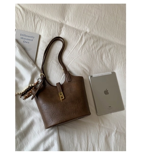 Close-up of brown vintage bucket bag with gold clasp and decorative beaded tassel