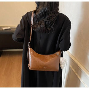 Close-up of brown oiled leather shoulder bag with a cute white plush bunny charm