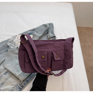 Detailed view of purple nylon shoulder bag with utility pockets and retro metal buckles