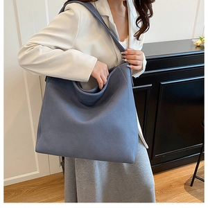 Detailed texture of dusty blue suede tote bag worn with a white casual blazer