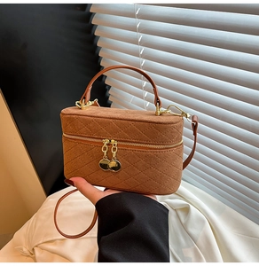 Macro view of brown quilted suede handbag showing gold zipper and circular charms