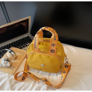Gelbe Nylontasche mit geometrischen Riemen und Laptop auf dem Schreibtisch